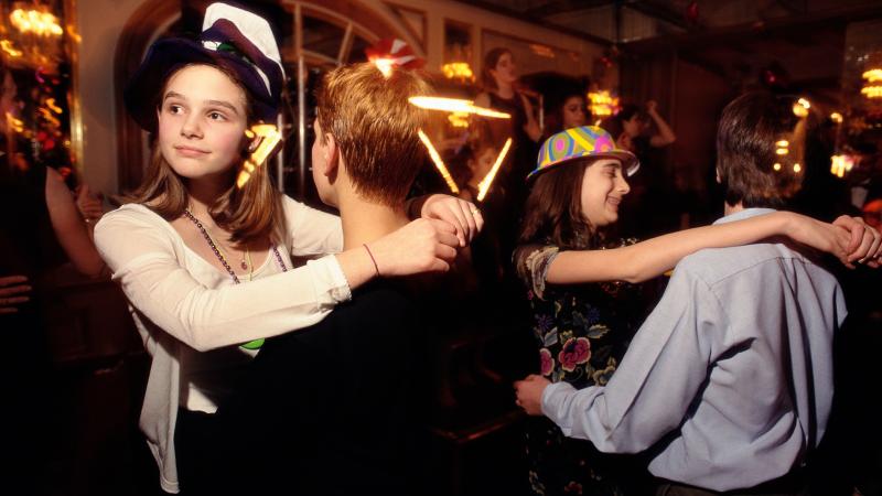 Two pairs of teenagers dancing, with the girls' arms on the boys' shoulders, and the boys' arms around the girls' waists