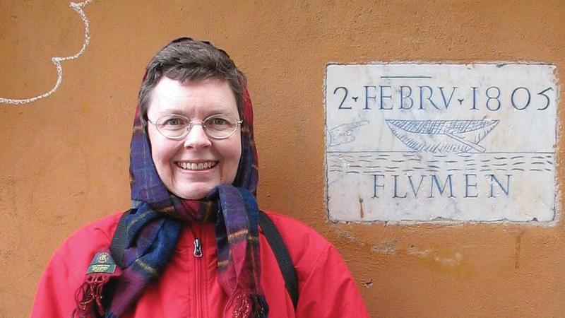 photograph of woman standing in front of a plaque