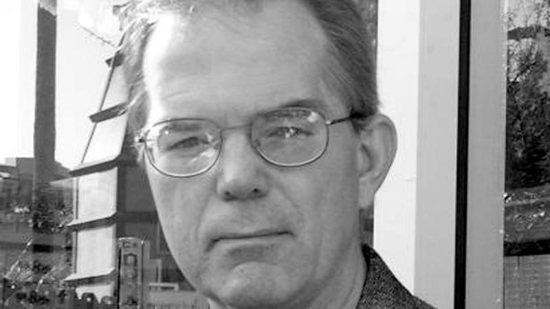 Black and white headshot of a man with glasses