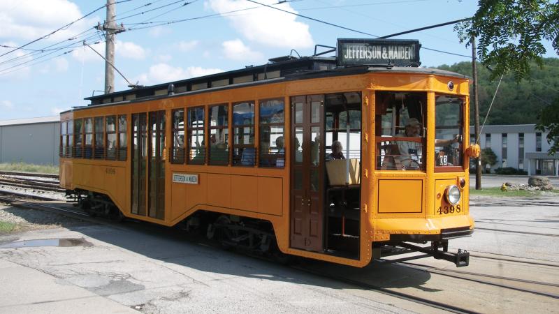 Color photo of a yellow trolley making its way.
