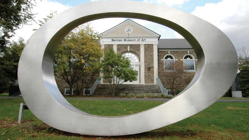 An artistic sculpture in an oval shape made of stainless steel before the Berman Museum of Art at Ursinus College.