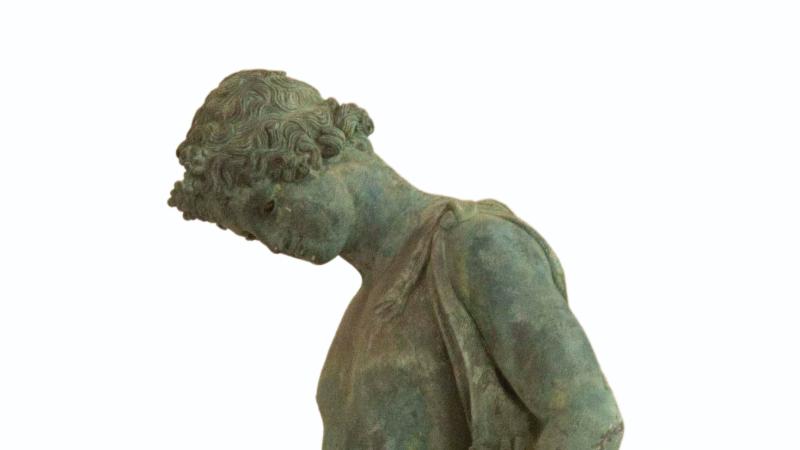 A bronze statue standing in a contemplative pose.