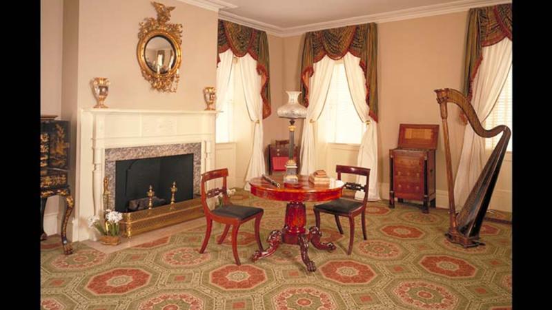 Color photo of an elegant parlor with a table and two chairs at its center.