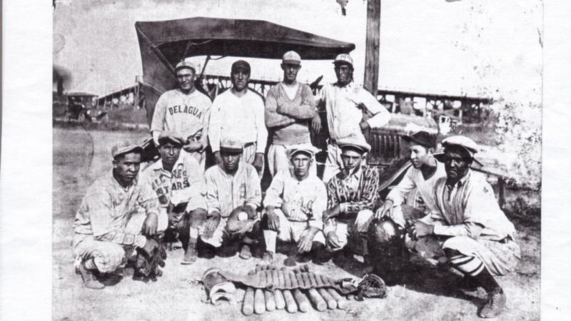 Black and white photo of a baseball team kneeling for a portrait.