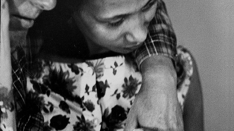 Black and white photo of a white man with his arm lovingly around the shoulder of a black woman.