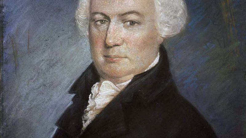 Portrait of a balding man in a black 18th century suit.