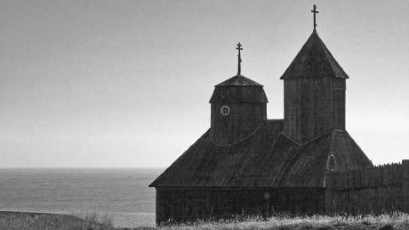 Black and white photo portrait of a seaside church with two cupolas. 