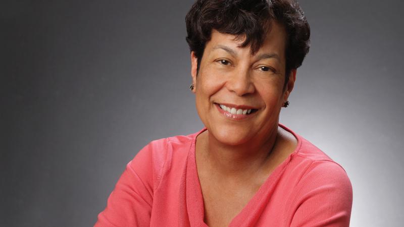 Color photo portrait of Carla Peterson in a pink blouse, with short hair.