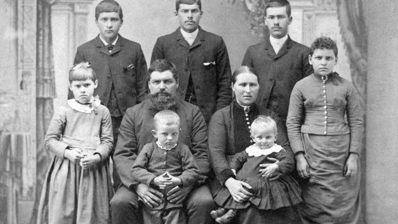 Black and white family portrait of three young children, their parents, and three brothers.