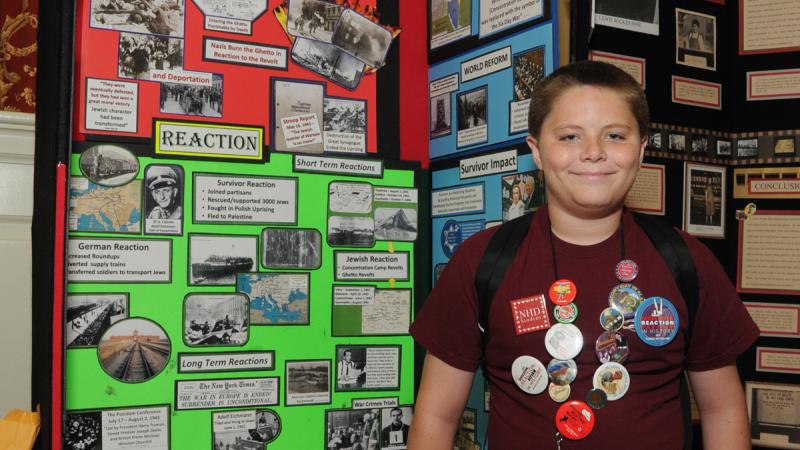 Photo of a young student standing in front of his history exhibit.