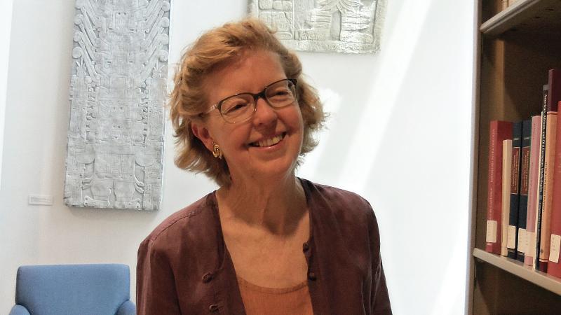 Color photo of Katherine Rinne standing with a book in her hands.