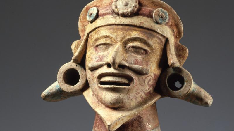 Photo of a Mixtec statue that is sitting with his mouth open, either chanting or laughing.