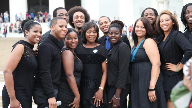 Color photo of a group of African-Americans posing in front of a camera.