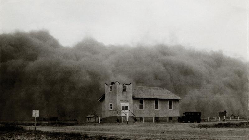 Black and white photo of a country church being engulfed by a giant dust cloud.