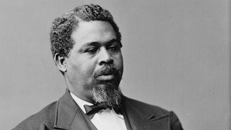 Black and white photo portrait of Robert Smalls wearing a suit and sitting down.