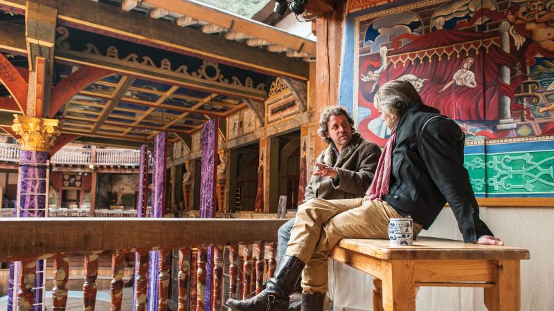 Irons and Dromgoole sit next to each other on a bench onstage, deep in conversation