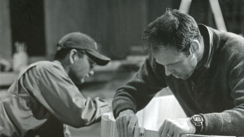 black and white photo of two men working on a piece of wood