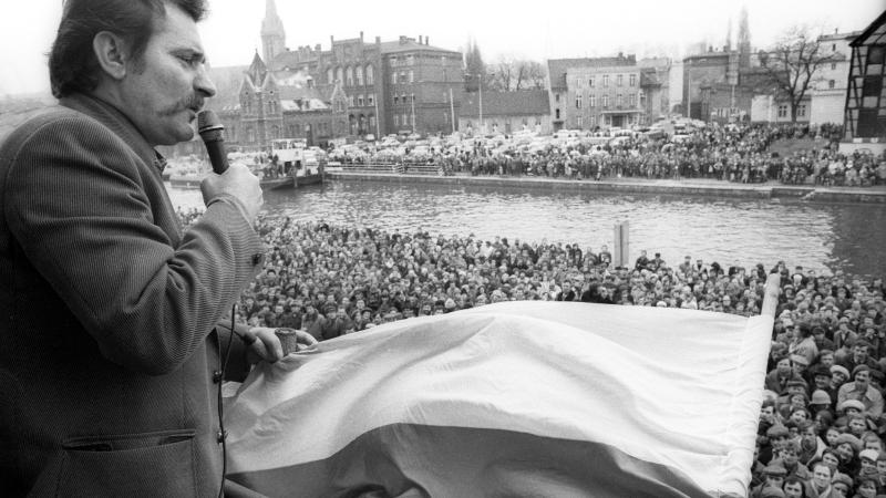 Black and white photo of a man speaking before a large crowd.