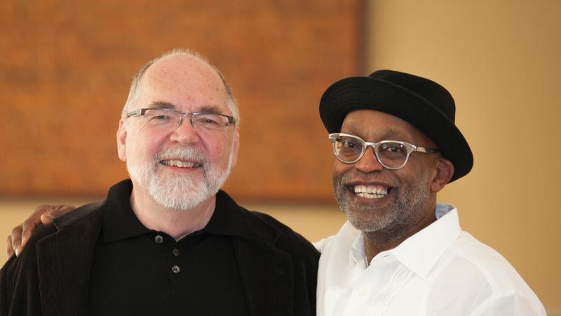 O'Fallon, black turtleneck and glasses, and Jones, wearing a black hat and glasses