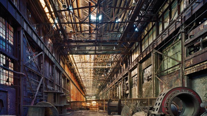 Color photo of the interior of an abandoned Ford Motors assembly plant. 
