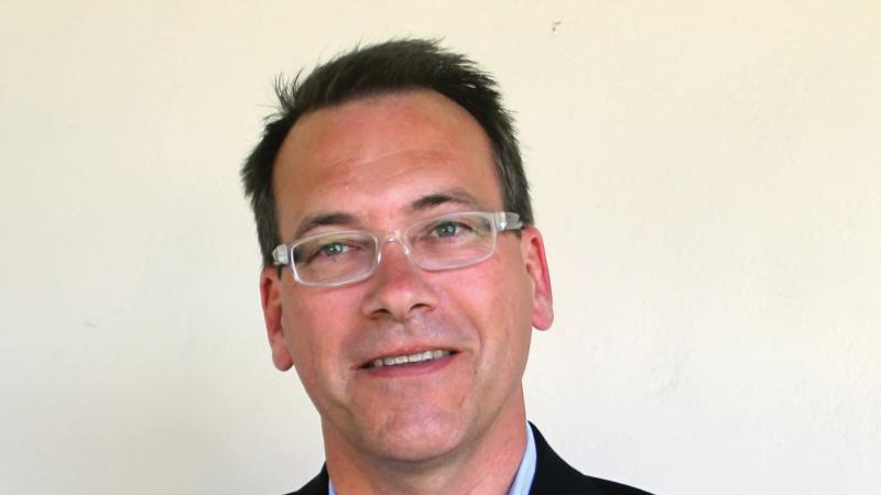 Color photo of David Igler wearing a blue collared shirt and black blazer.