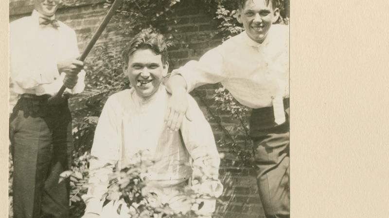 An old photograph of the Mencken brothers in their backyard. One of them is holding an oar over H.L. Mencken's head.