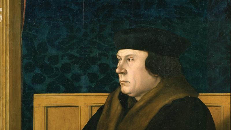 Color painting of Thomas Cromwell in regal dress, sitting at a desk draped with an elegant green tablecloth.