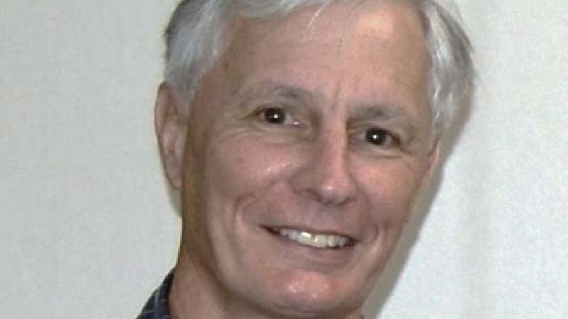 Russell, with white hair, wearing a black and white grid patterned shirt