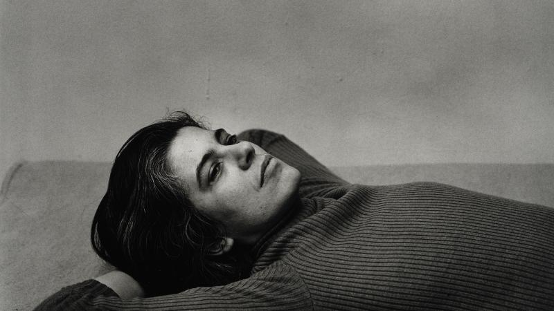 black and white photo of Sontag, lying down with her hands underneath her head