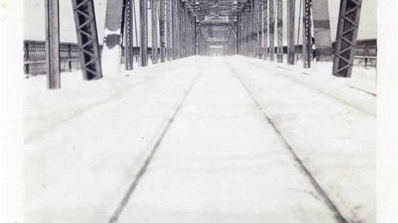 Black and white photo of a bridge, looking down it.