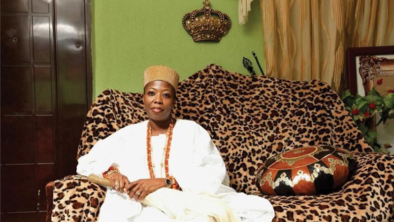 HRM Princess Dr. Adetutu Adebiyi Adesida, seated on a leopard print couch, wearing a write dress