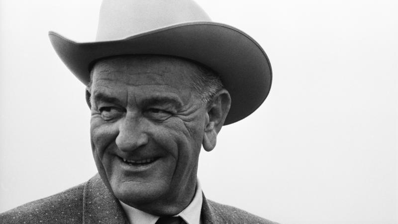 Black and white photo of a man in a suit smiling.