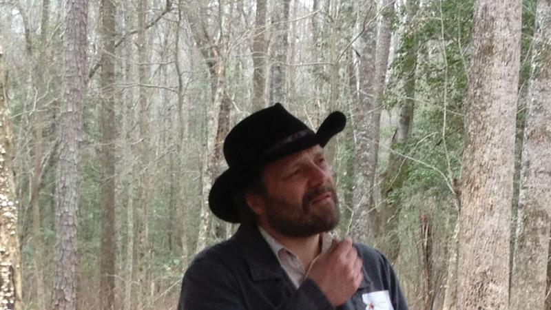 Color photo portrait of Daniel Sayers wearing a black cowboy hat and jacket.