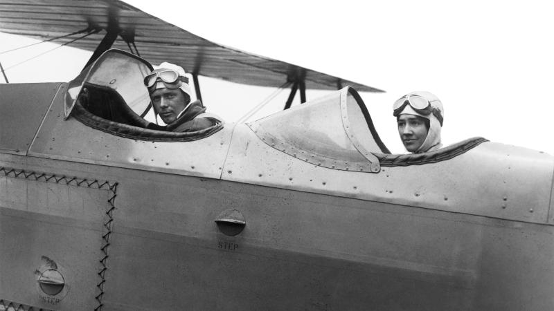 Black and white photo of the Lindbergh brothers in an airplane with an open cockpit.