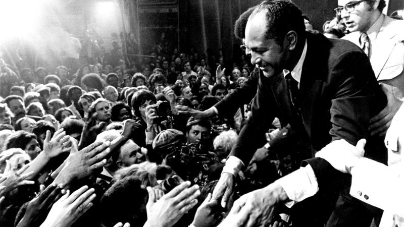 Mayor-elect Tom Bradley shaking hands with a crowd of people, reaching out their hands to him