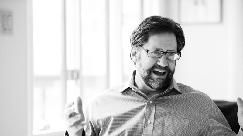 black and white photograph of a man speaking, gesturing with his hands