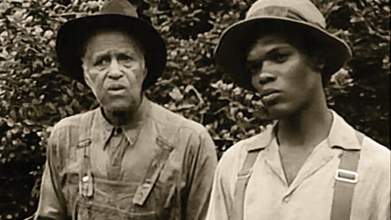 black and white film still of two men in farming clothes