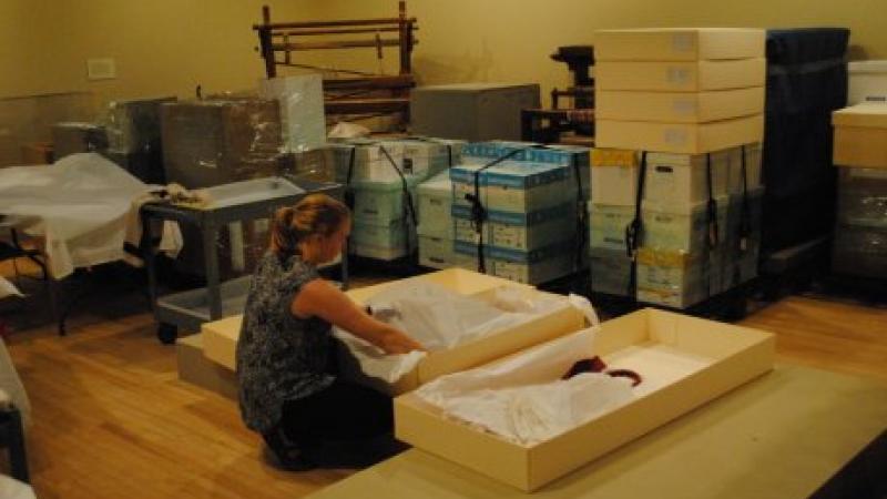 woman packing costumes into large boxes