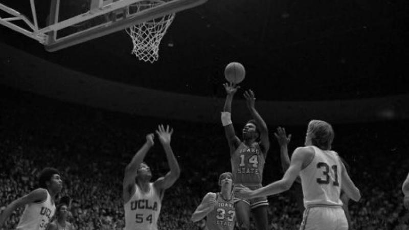 black and white photo of men playing basketball