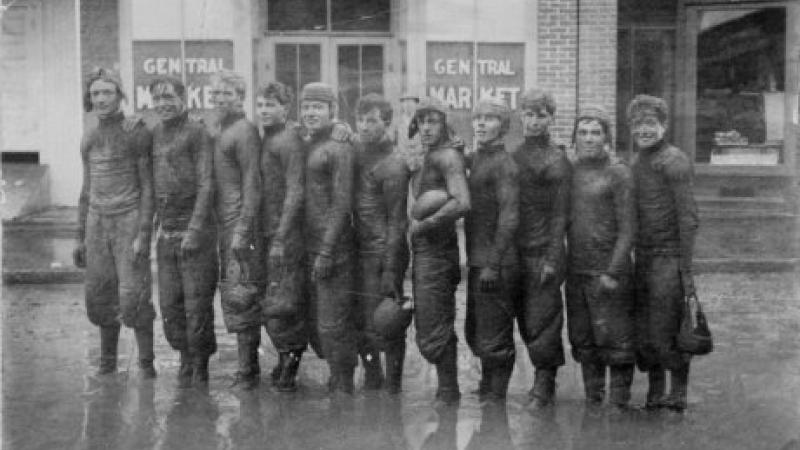 black and white photo of football team standing in the rain