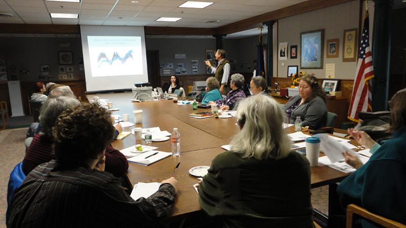 people sitting at conference table, man giving presentation