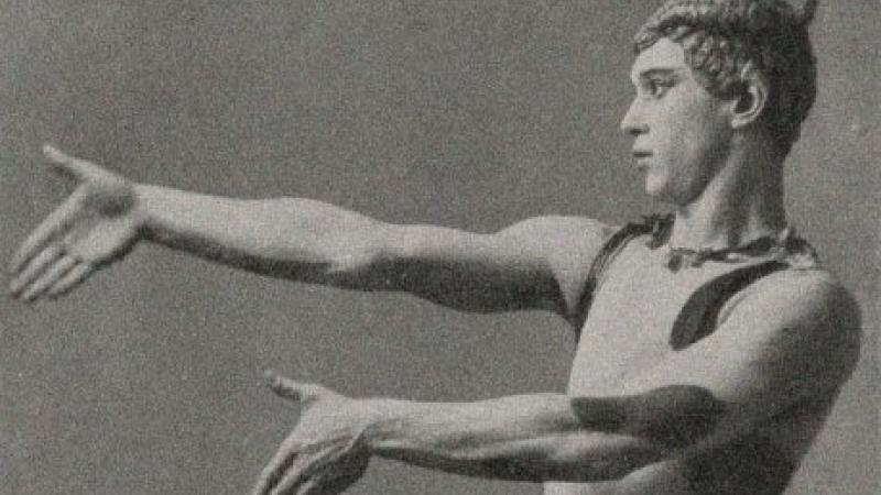 Black and white portrait of a man standing in a ballerina pose with his arms extended.