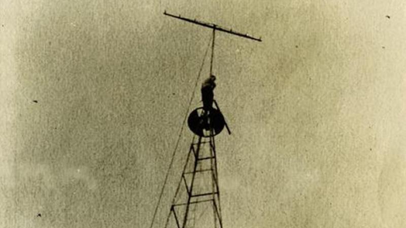 Radio tower with a man near top by antenna at Graceland College, Lamoni, Iowa.