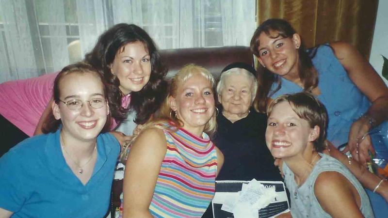 Group photo of Sendler and the girls from Life in a Jar, 2002. Sendler is sitting in a brown leather sofa with the girls surrounding her.