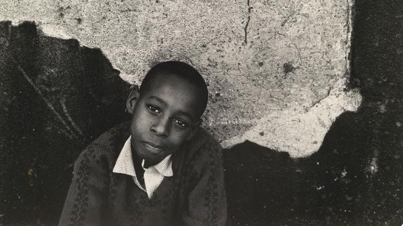 photo of a young a boy around nine years old posing before a cracked cement wall