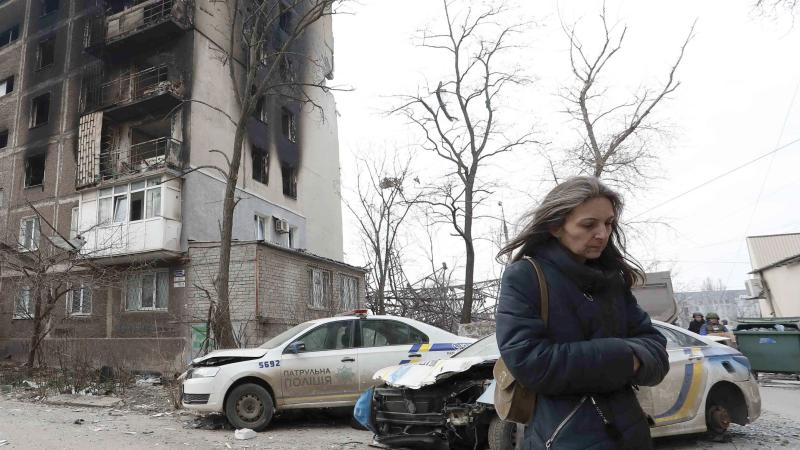 Woman walking in Mariupol, Ukraine, amidst the rubble of war. 