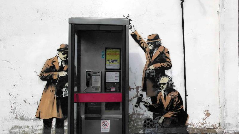 mural of spies tapping into a real phone booth in England