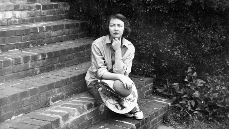Black and white image of Flannery O Connor seated on steps