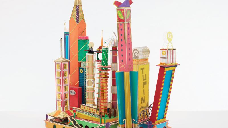 Photograph of a cityscape constructed by Bodys Isek Kingelez with approximately a dozen brightly-colored buildings.