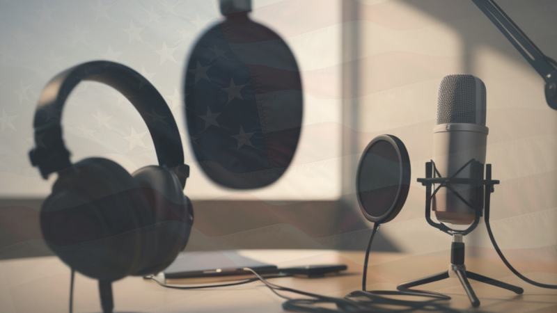 Podcasting equipment with a set of headphones and three microphones with a faint American flag overlay